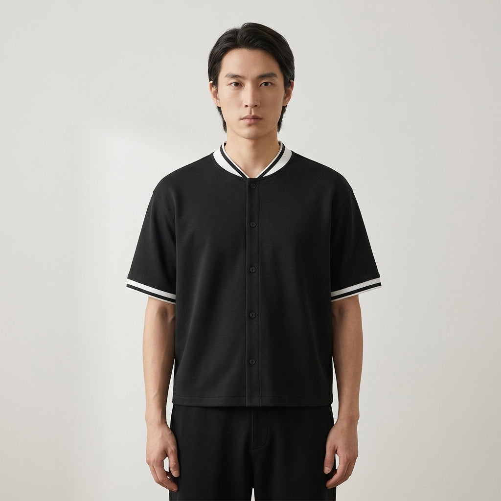 Black oversized baseball jersey with a loose fit and striped sleeve trim, front view on a model.