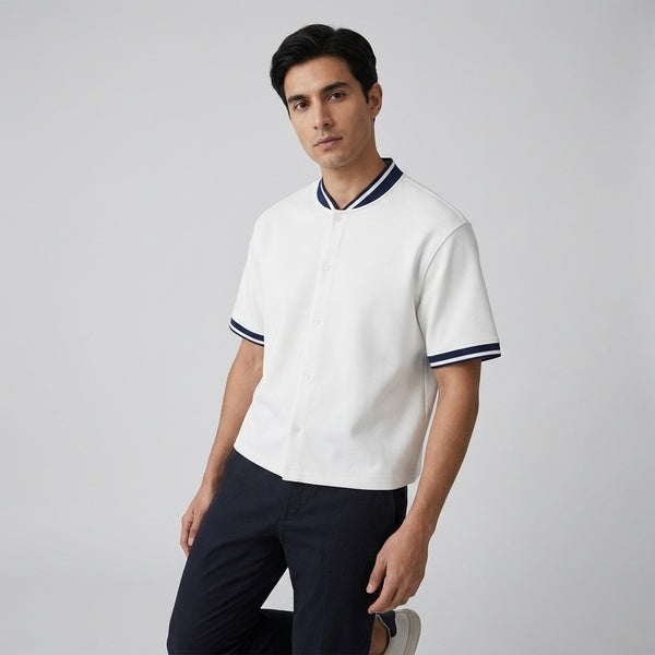 White oversized baseball jersey with navy striped collar and cuffs, styled with dark pants.
