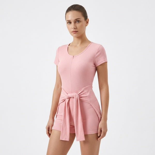 Pink short-sleeve tie-waist romper, close front view showing the scoop neckline and tied waist panel.