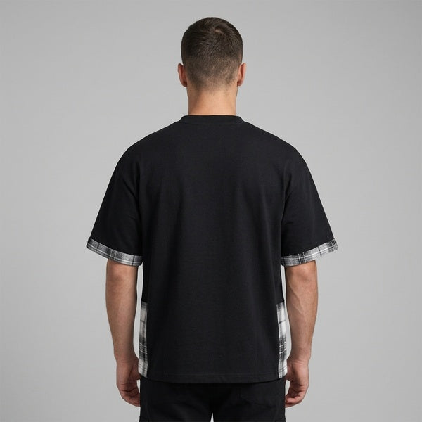 Back of the black plaid paneled T-shirt showing the plain back and plaid sleeve and side panels.
