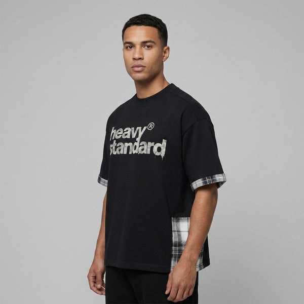 Black plaid paneled T-shirt with a Heavy Standard chest graphic, three-quarter front view on a model.