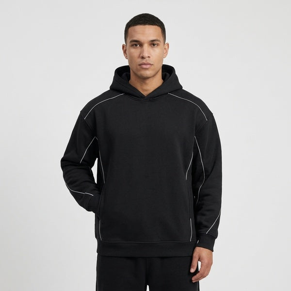 Black Unisex Oversized Piping Fleece Hoodie on a model, showing contrast piping along the shoulders and body.