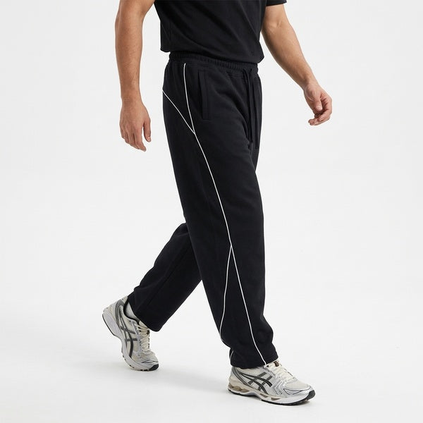 Black piping fleece barrel-leg sweatpants, model walking in a side view.