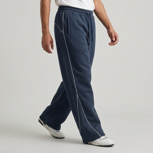 Navy piping fleece barrel-leg sweatpants, model walking in a side view.