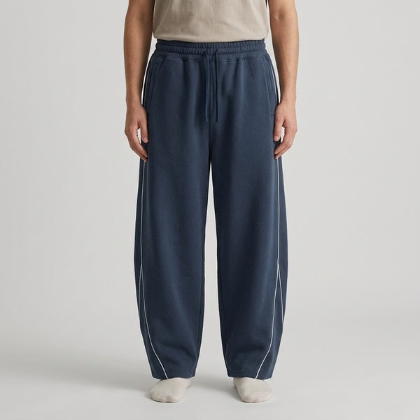 Navy piping fleece barrel-leg sweatpants, model in a straight front view.