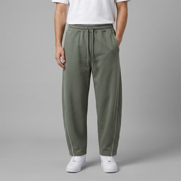 Muted gray-green piping fleece barrel-leg sweatpants, model in a straight front view.