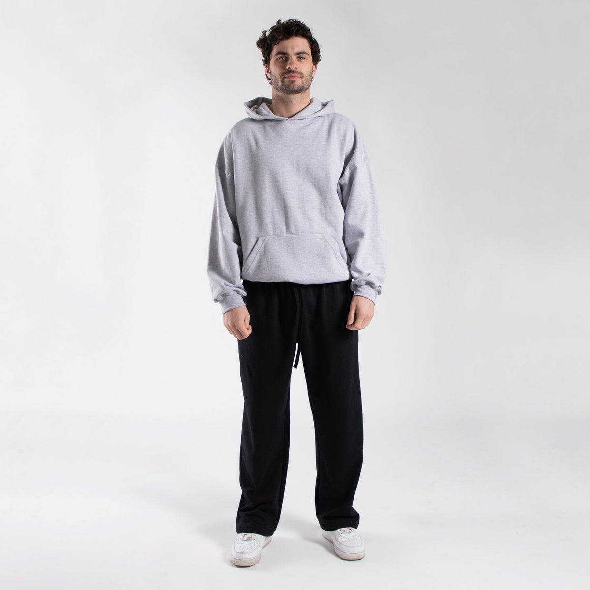 Athletic gray oversized fleece hoodie worn with black pants, full front view.