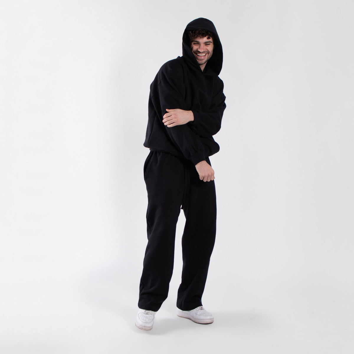 Black oversized fleece hoodie with the hood up, styled with black pants.