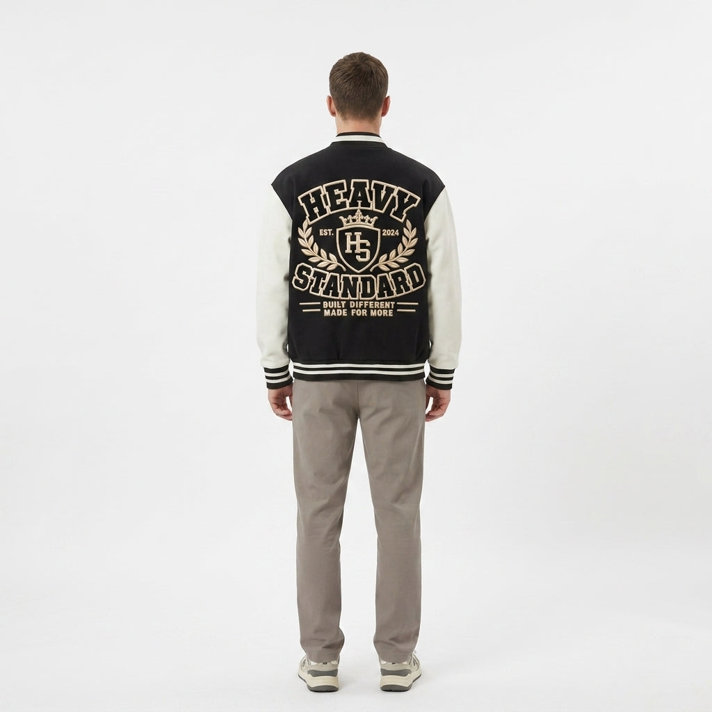 Back view of the black and cream Two-Tone Fleeced Varsity Jacket with a large Heavy Standard graphic.